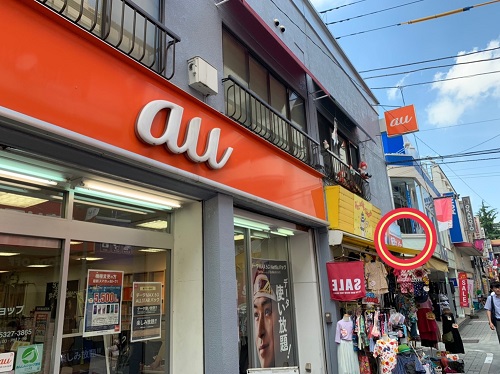 左手の看板を探します。 商店街の左側に、当店の赤と青の看板が見えてきます。