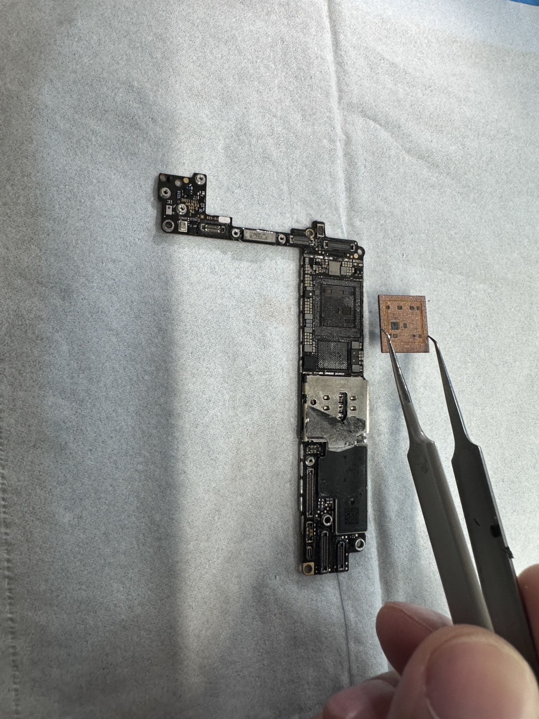 スマートフォンの基板から取り外したICチップを、ピンセットで扱っている様子。